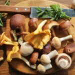 Mix of forest mushrooms on cutting board over old wooden table .